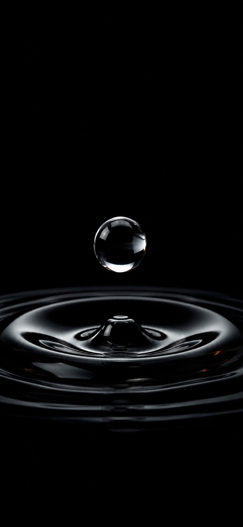 Water drop wallpaper falling onto dark rippling surface in black and white